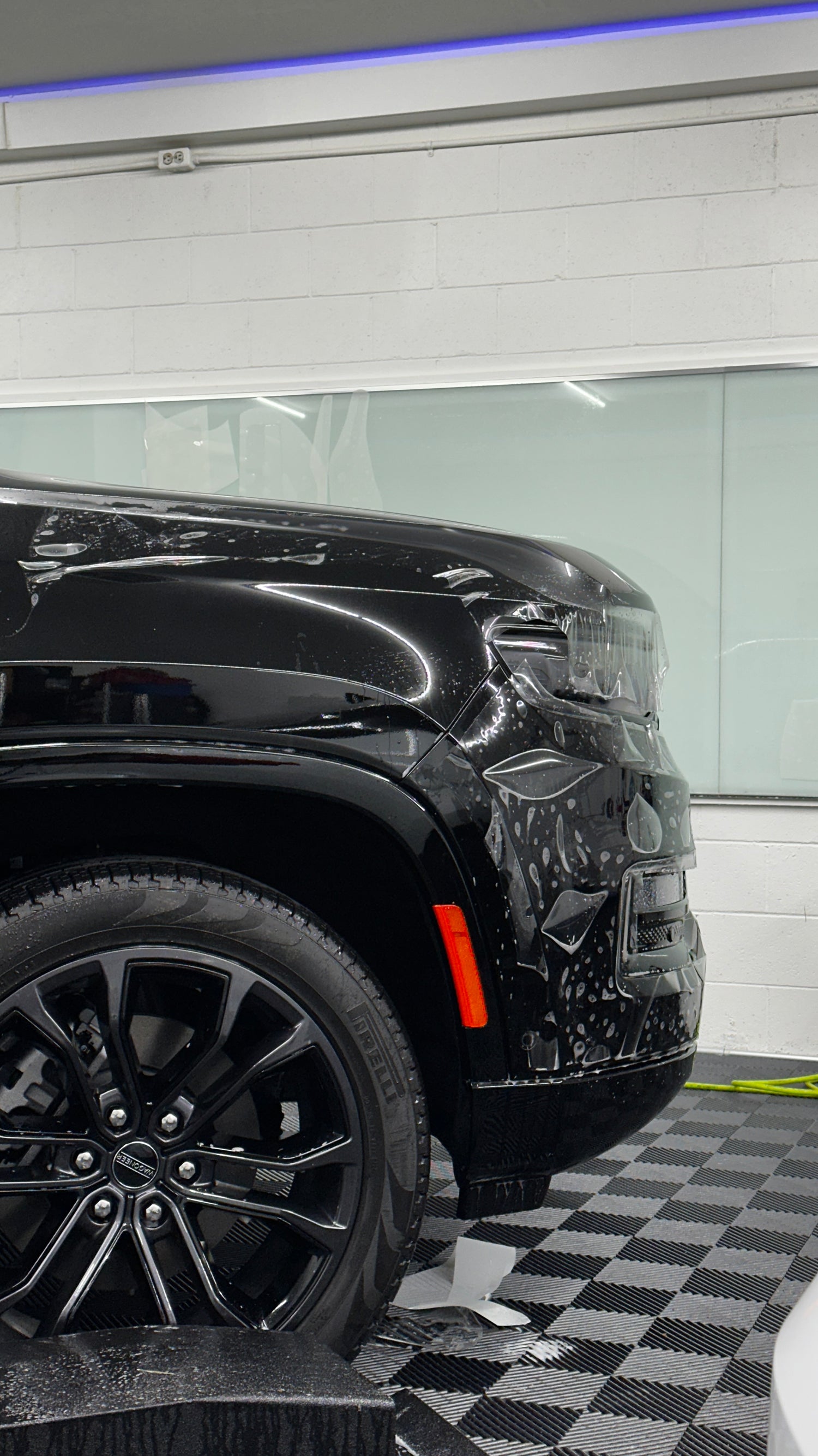 Black SUV inside a car wash tunnel with checkered floor