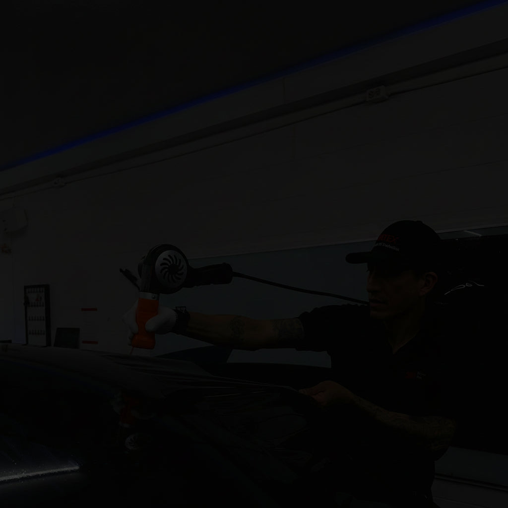 Person applying car wrap to a vehicle in a garage