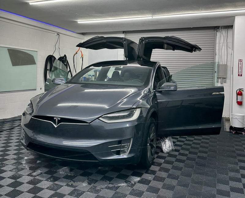 Car interior with open doors in a checkered floor area, possibly in a service or repair shop.